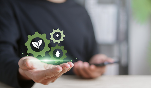 person holding smartphone with green gears icons representing energy, water, and plant sustainability solutions for 4 environmental benefits
